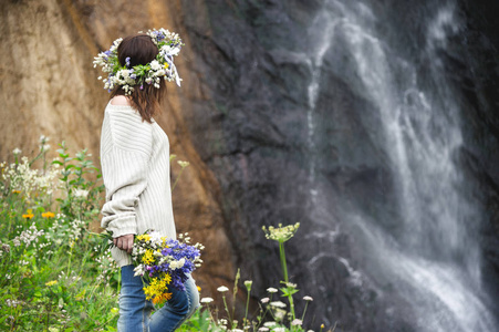 一个女孩用她的头和一束鲜花在她的手对瀑布花环的肖像