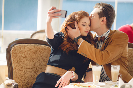 年轻夫妇坐在咖啡馆里用手机看照片