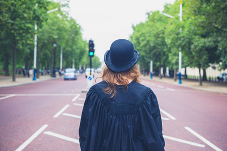 在街上的帽子和毕业礼服的女人
