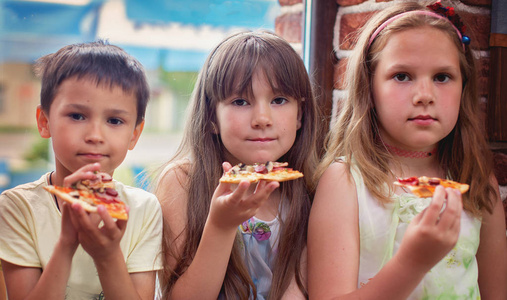 快乐的孩子们吃比萨饼, 一起玩得开心