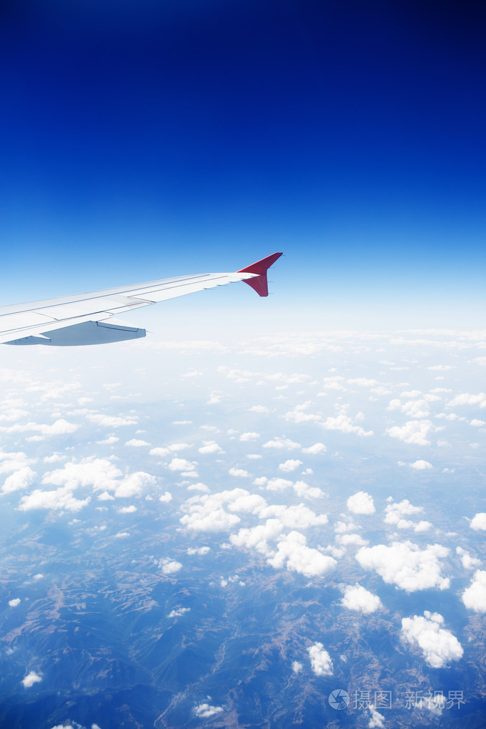 飞越云层和山脉的飞机的机翼.