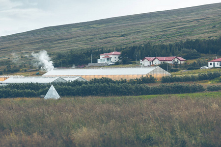 地热温室和在绿色的山丘上的房子