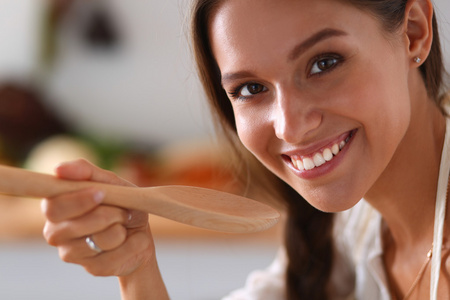 烹饪的女人,在厨房里用木勺照片