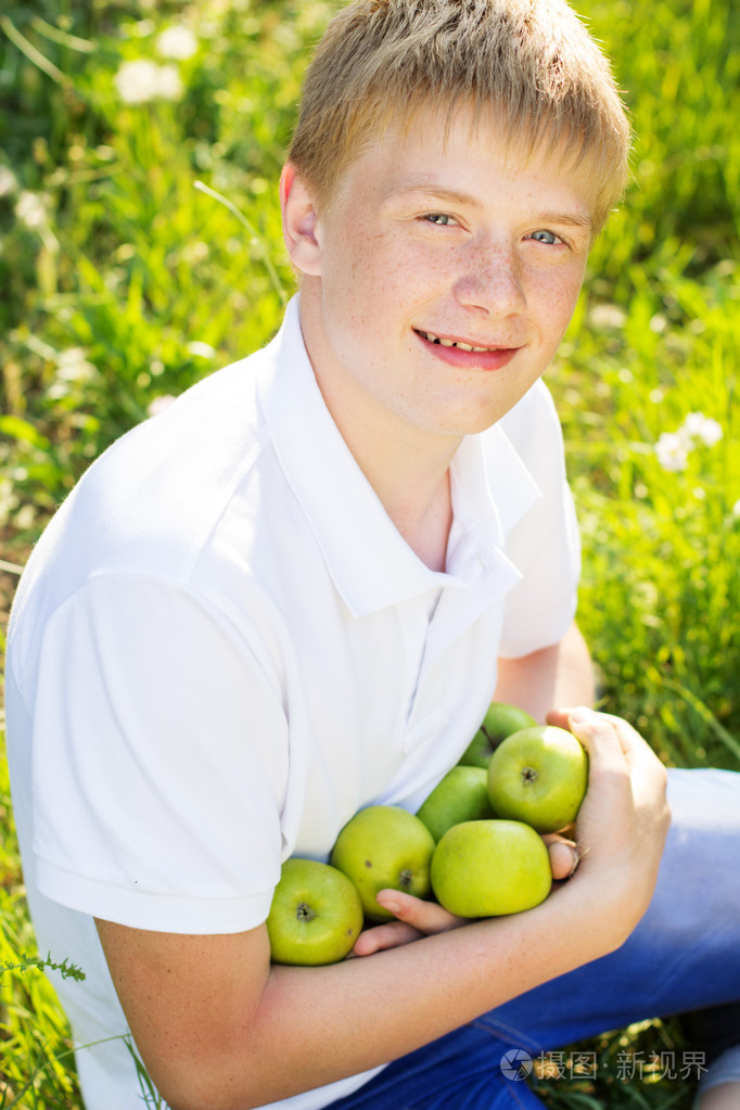 青少年的漂亮男孩握着青苹果