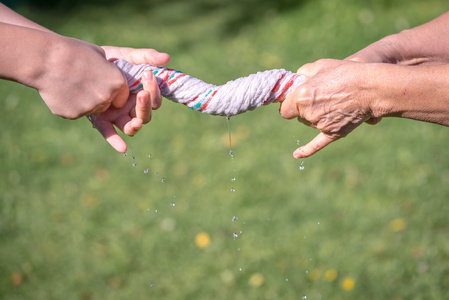 拧抹布手挤压湿的织物上草背景照片