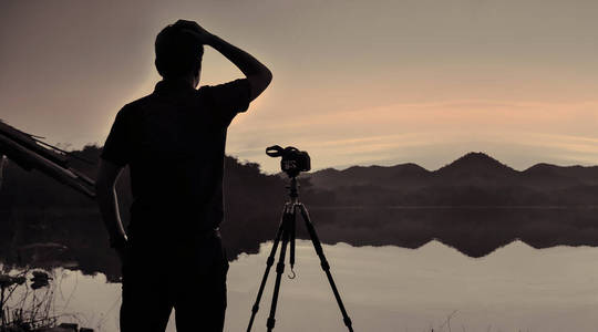 摄影师在水库在日落, 泰国