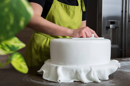 无法辨认装饰与白色翻糖婚礼蛋糕的面包店里的女人