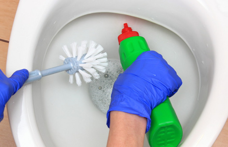 蓝色手套清洗马桶的女人的手照片