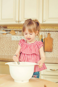 可爱的小帮手女孩帮助她的妈妈在厨房做饭。快乐充满爱的家庭准备的面包店