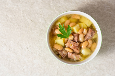 土豆 豆类和韭葱石背景上的陶瓷碗里的牛肉汤