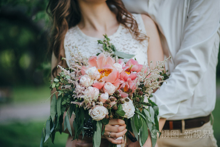 一对夫妇捧着一束粉红色和白色牡丹花和绿色