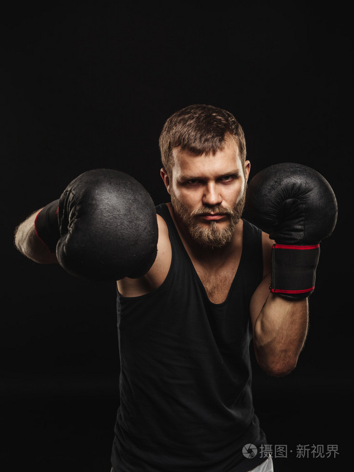 戴着手套在深色背景上的竞技胡子的拳击手