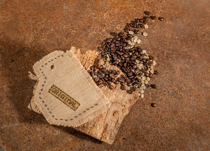 一个用黄麻缝制的杯子，上面放着咖啡豆和旧木头