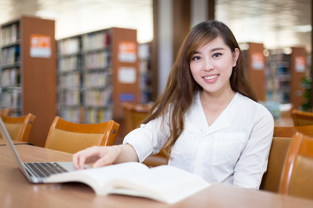 亚洲女学生在图书馆中使用笔记本电脑