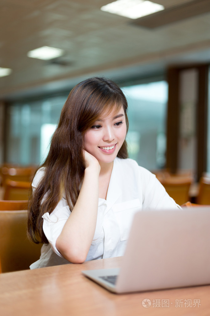 女留学生在图书馆与笔记本电脑