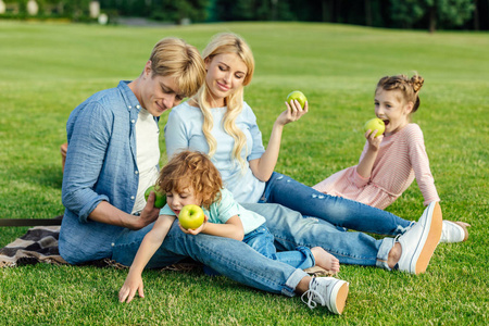 在公园里的家庭吃苹果。