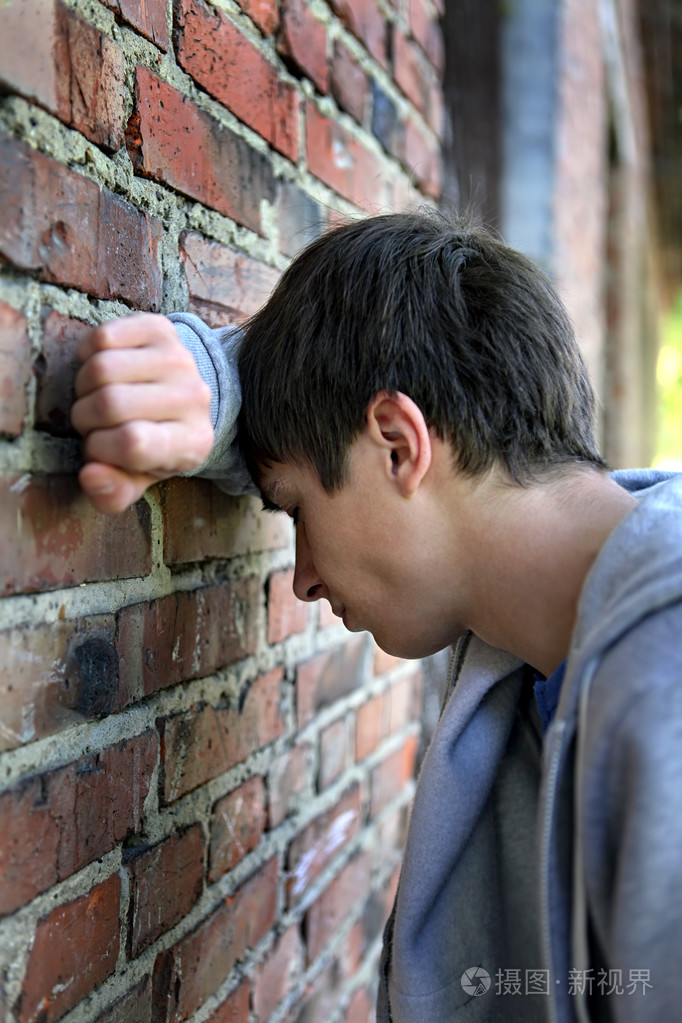 悲哀的年轻人靠在墙边