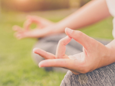 女人瑜伽手指与周围背景的大自然代理手上的软焦点。健康的生活方式和松弛的概念