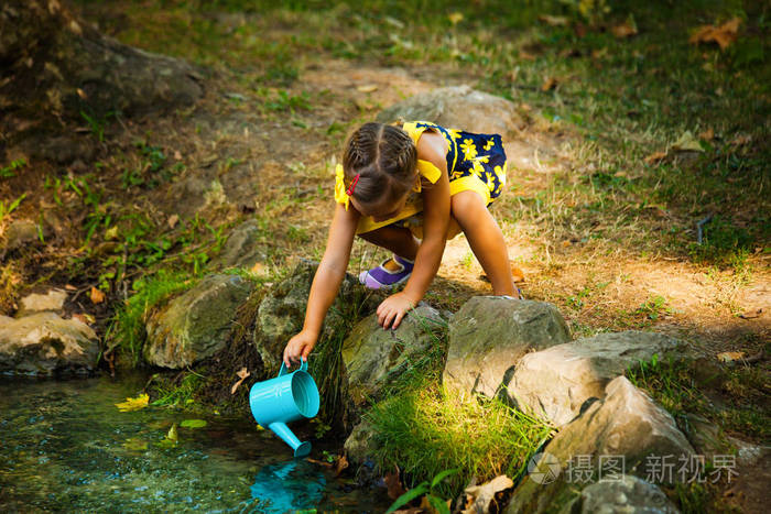 可爱的小女孩从流中桶打水