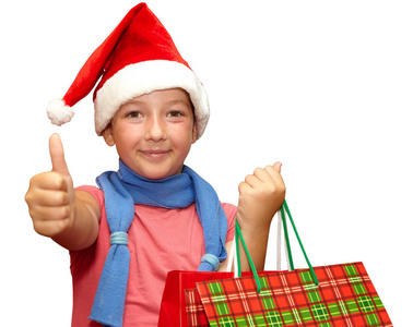 在与购物袋顶红色的帽子的小女孩。圣诞节