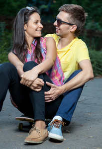 年轻夫妇的爱情坐在户外滑板