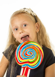 美丽的女孩子，用长长的金发吃舔巨大螺旋棒棒糖糖果快乐的笑