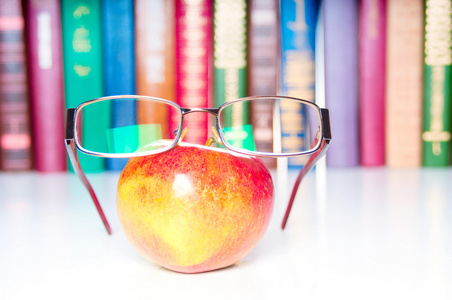 苹果与眼镜和五彩斑斓的图书，在背景上