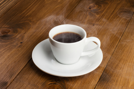 白杯热气腾腾的咖啡，木制的桌子上