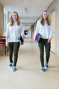 两个荷兰少女走在学校长走廊执行