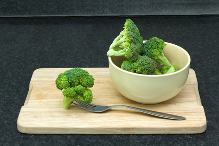 绿色的新鲜蔬菜。用叉子在一碗在菜板上西兰花