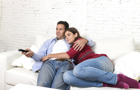 一对相爱的情侣在家沙发上拥抱，放松地看电影
