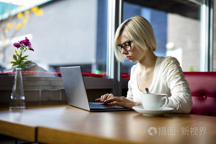 青年集中在咖啡厅的笔记本电脑上工作的女人