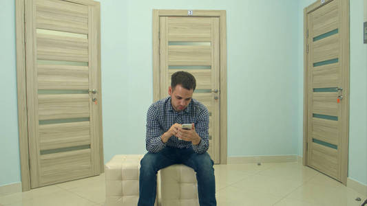 在等待他的医生预约时使用手机的男性病人