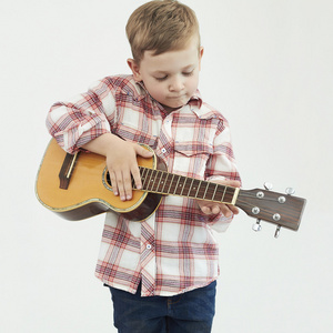 有趣的孩子男孩吉他。时尚的乡下男孩玩音乐
