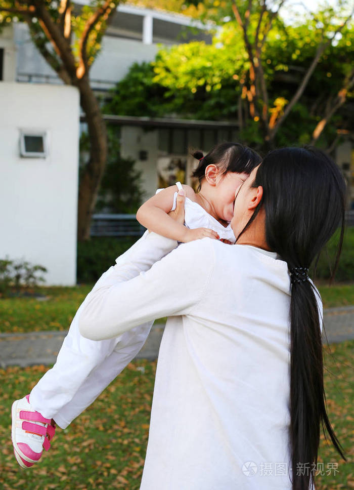 在母亲的小亚洲女孩拥抱在公园