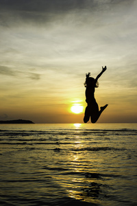 女孩跳跃欢迎海滩日出