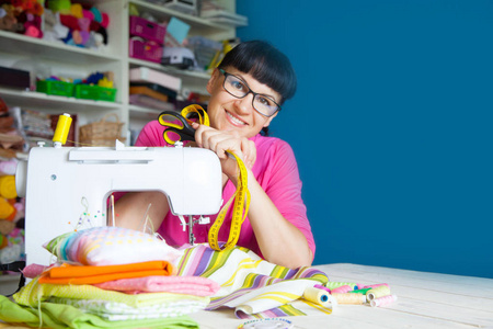 幸福微笑的女人旁边一台缝纫机。布 线程和