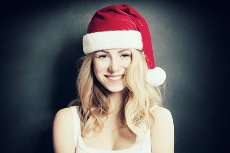 圣诞女人笑。美丽的圣诞节时尚模型在圣诞老人的帽子