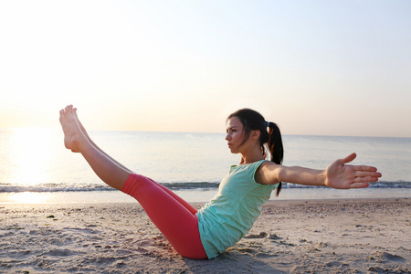 女人做瑜伽在海滩上