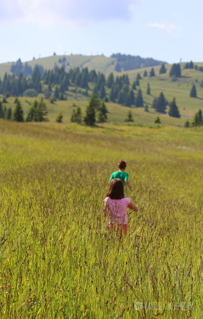 2两个孩子在山地草地上高大的草地上奔跑