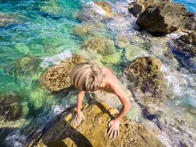 在海边的岩石上的青少年夏季