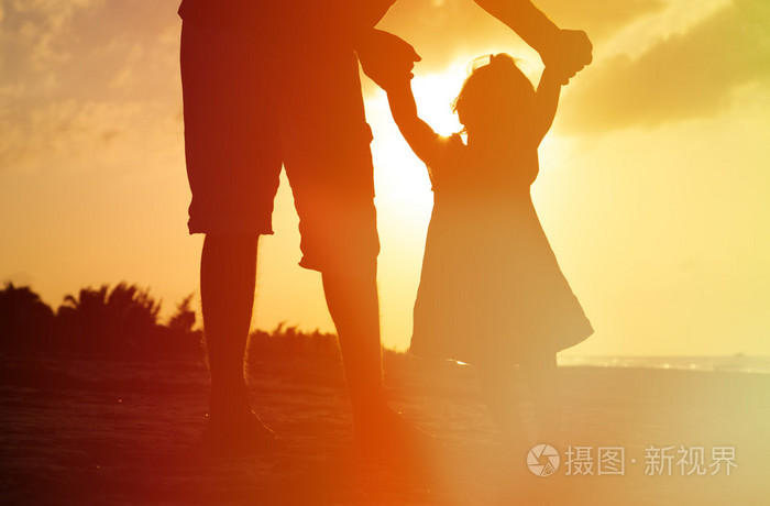 父亲和在海滩上的小女儿的剪影