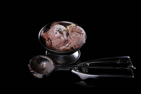 水果和巧克力冰淇淋与在黑色背景上孤立的金属碗勺