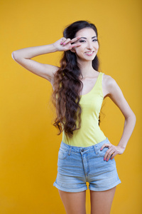 时尚亚洲的年轻女孩。在黄色背景上的肖像