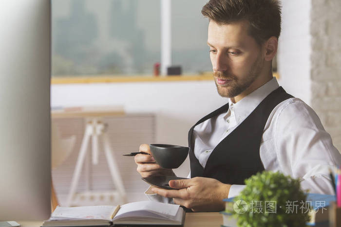 英俊的男人喝咖啡在工作场所照片-正版商用图片0d19on-摄图新视界