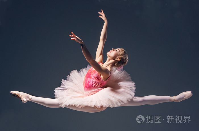 美丽的女芭蕾舞演员跳上一个灰色背景