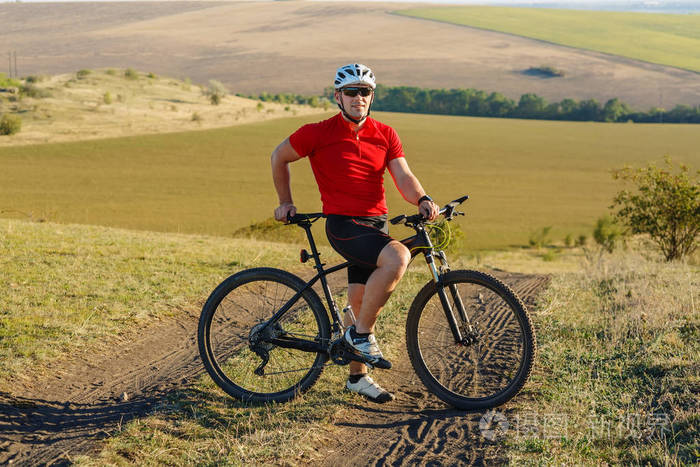 在乡间小路上骑自行车旅游.在背景上的日落