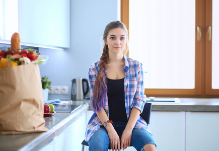 双臂交叉厨房背景下站的年轻女子的肖像