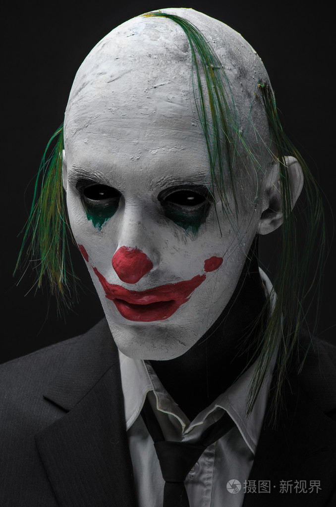 可怕的小丑和万圣节主题: 疯狂可怕的绿色小丑在孤立在工作室中的黑暗