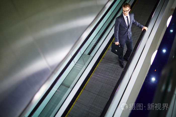 公文包站在自动扶梯上的商人
